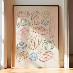 May include: A framed print featuring a variety of bread illustrations in shades of pink, brown, blue, green, and yellow. The artwork includes a croissant, baguette, pretzel, and other baked goods. The print is displayed on a light-colored background.