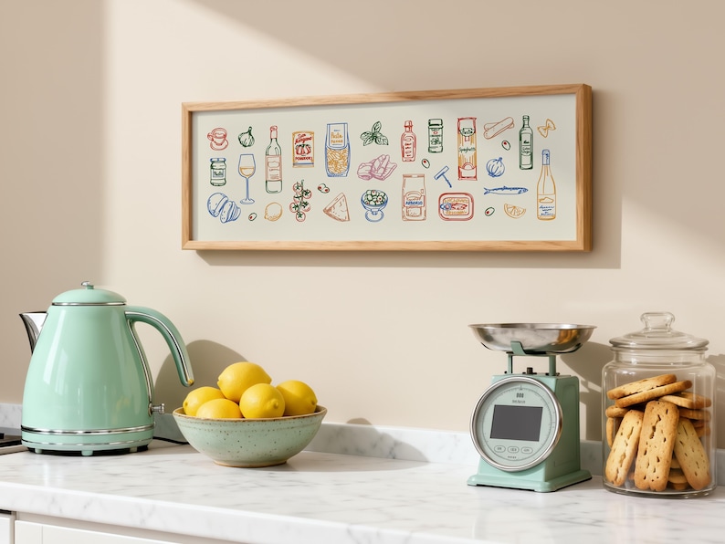 May include: A kitchen scene features a framed print with food illustrations, a mint green kettle, a bowl of lemons, a scale, and a jar of cookies. The print has a light wood frame and the illustrations are in various colors.