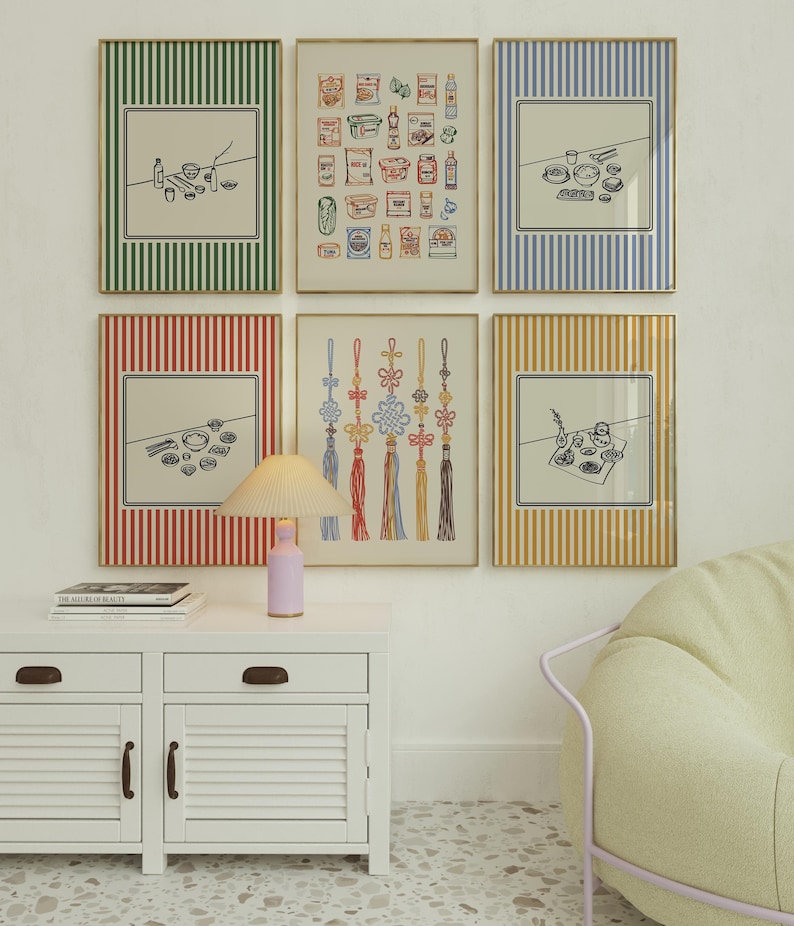 Puede incluir: Una colecci&oacute;n de l&aacute;minas art&iacute;sticas enmarcadas con varios dise&ntilde;os. Las l&aacute;minas presentan dibujos lineales de alimentos, nudos decorativos y otros objetos. Los marcos tienen bordes a rayas de colores en verde, azul, rojo y amarillo. Un mueble blanco con una l&aacute;mpara y una silla est&aacute;n en primer plano.
