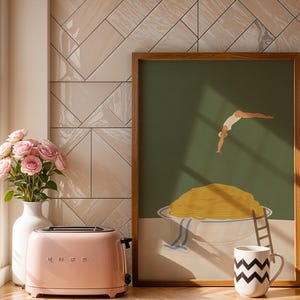 May include: A pink retro-style toaster sits next to a vase of pink roses and a framed art print. The art print features a person diving into a bowl of spaghetti. A black and white zig-zag patterned mug is also visible.