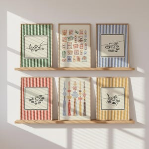 Puede incluir: Seis impresiones art&iacute;sticas enmarcadas con marcos de madera se exhiben en estantes de madera. Las impresiones presentan varias ilustraciones, incluidos alimentos, adornos tradicionales coreanos y arreglos minimalistas de alimentos, sobre fondos a rayas en verde, azul, rojo y amarillo.