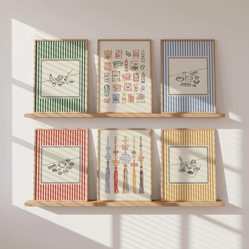 Puede incluir: Seis impresiones art&iacute;sticas enmarcadas con marcos de madera se exhiben en estantes de madera. Las impresiones presentan varias ilustraciones, incluidos alimentos, adornos tradicionales coreanos y arreglos minimalistas de alimentos, sobre fondos a rayas en verde, azul, rojo y amarillo.