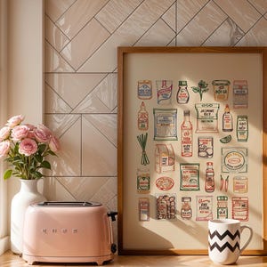 May include: A pink SMEG toaster sits next to a white vase with pink roses and a framed print of Asian food items. A white mug with a black zigzag pattern is in front of the print.