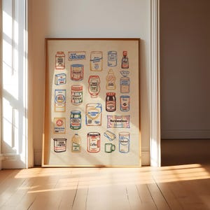 May include: A framed print featuring colorful illustrations of various grocery items, including pasta sauce, crackers, peanut butter, pickles, sugar, salt, ketchup, honey wheat, baking soda, cocoa powder, coffee, and oatmeal. The artwork is displayed on a light beige background.
