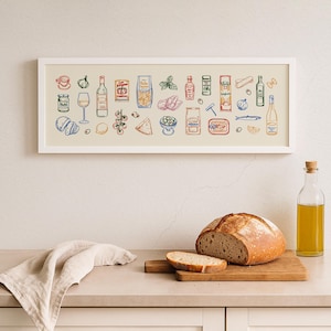 May include: A framed print featuring colorful illustrations of Italian food items, including pasta, wine, and olives. A loaf of bread, a slice of bread, and a bottle of olive oil are on a wooden cutting board. A linen napkin is draped on the counter.