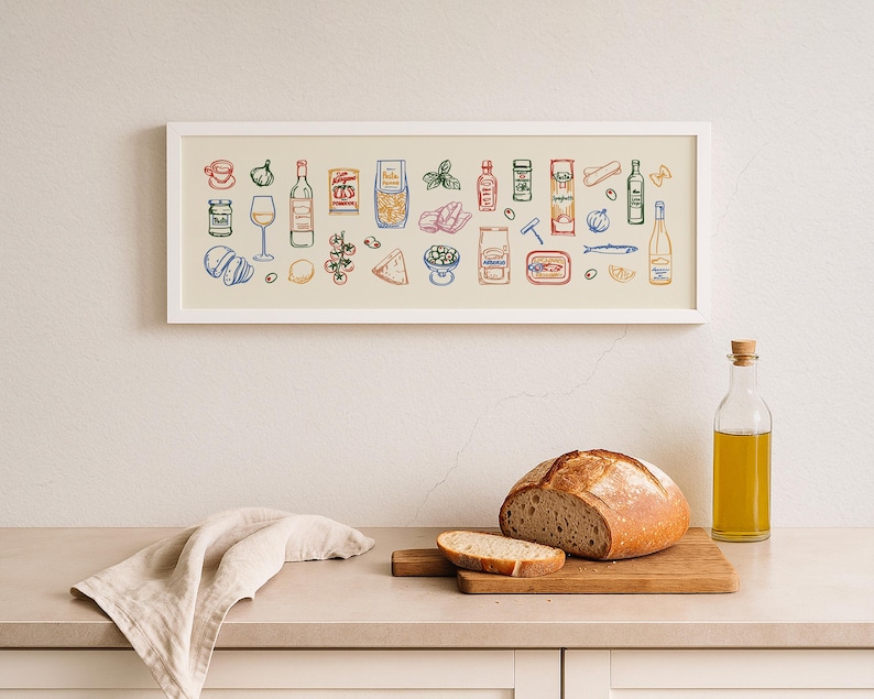 May include: A framed print featuring colorful illustrations of Italian food items, including pasta, wine, and olives. A loaf of bread, a slice of bread, and a bottle of olive oil are on a wooden cutting board. A linen napkin is draped on the counter.
