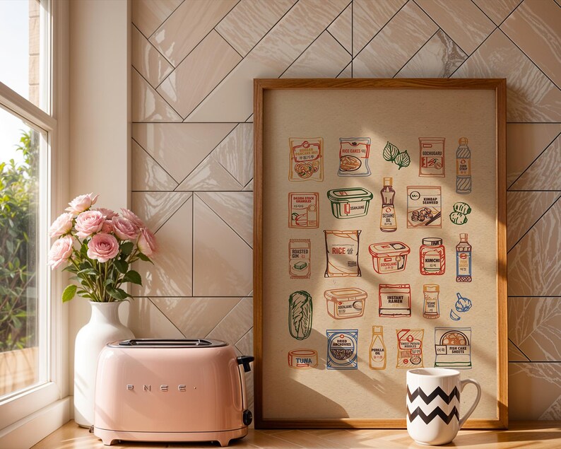 Puede incluir: Una tostadora rosa SMEG se encuentra junto a un jarr&oacute;n blanco con rosas rosas y una impresi&oacute;n enmarcada de alimentos ilustrados. Una taza blanca con un patr&oacute;n de zigzag negro est&aacute; en el mostrador. El fondo presenta una pared de azulejos claros.
