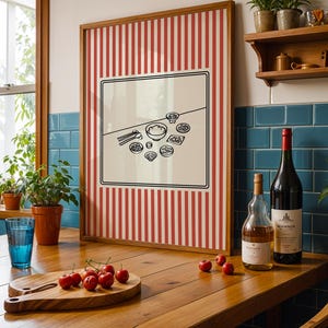 Puede incluir: Una obra de arte enmarcada con un fondo a rayas rojas y blancas y una ilustraci&oacute;n en blanco y negro de alimentos. Una tabla de cortar de madera con cerezas, un vaso azul y botellas de vino est&aacute;n sobre una mesa de madera.