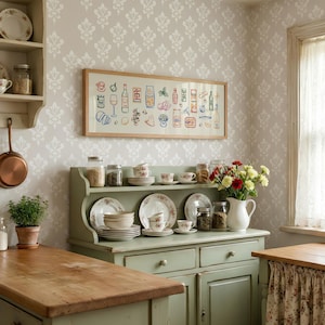 May include: A kitchen scene with a light green cabinet, shelves, and a wooden countertop. A framed artwork with food illustrations hangs above the cabinet. Dishes, jars, and a vase of flowers are displayed. A small potted plant and a copper pan are also visible.