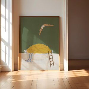 May include: A framed art print depicts a whimsical scene of a person diving into a large bowl of yellow spaghetti. A small wooden ladder leans against the bowl, and a blue and white striped towel hangs over the side. The background is a solid green.