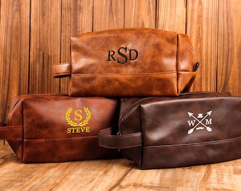 Puede incluir: Tres neceseres de cuero marrón con diseños bordados. La bolsa superior es de color marrón claro con las iniciales "RSD". La bolsa del medio es de color marrón oscuro con el nombre "STEVE" dentro de una corona dorada. La bolsa inferior es de color marrón oscuro con un diseño blanco.