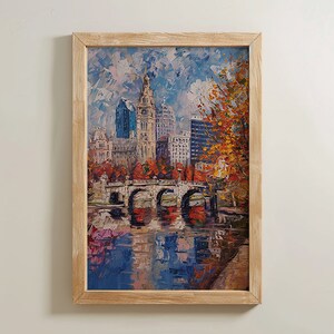 May include: A framed painting depicting a city skyline with a bridge spanning a river. The buildings are rendered in a range of colours, including yellow, blue, and red. The bridge is painted in a light brown hue. The river is painted in a blue colour with reflections of the buildings and bridge. The sky is painted in a light blue colour with white clouds. The painting is framed in a light brown wooden frame.