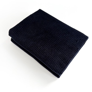 May include: Folded navy blue corduroy fabric, showcasing a ribbed texture. The fabric is neatly folded, displaying the rich color and tactile quality of the material. The image is shot against a white background, highlighting the fabric's details.