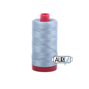 May include: A spool of light blue thread with a red base and top. The thread is tightly wound, and the spool has the "AURIfil" logo on the side. Ideal for sewing and crafting projects.