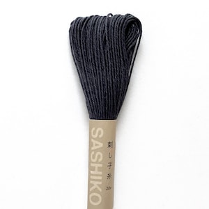 May include: A bundle of dark gray Sashiko thread, with the brand name and Japanese text printed on the label. The thread is tightly wound, and the label is a light tan color.