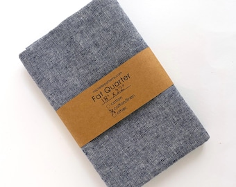 May include: A folded piece of dark blue fabric with a textured weave, wrapped in a brown paper band labeled michellepatterns.com Fat Quarter 18 inches by 22 inches, with checkboxes for cotton, cotton/linen, and other material options printed.