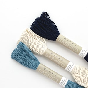 May include: Three spools of Sashiko thread in navy blue, cream, and teal. Each spool is labeled with Japanese text and the brand name "Sashiko". The thread is 20 meters long and made of 100% cotton.