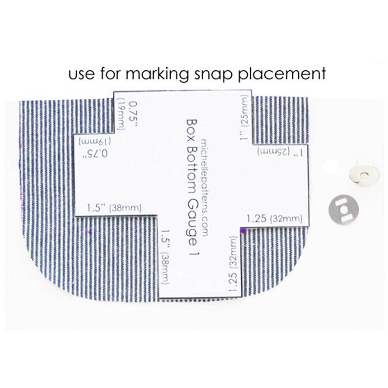 May include: A white guide with measurements in inches and millimeters for marking snap placement on fabric. The guide is labeled "Box Bottom Gauge 1" and includes the website address "michellepatterns.com".