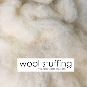 May include: Close-up of fluffy, off-white wool stuffing. The image features a dense, textured material, ideal for crafts and filling projects. The text "wool stuffing" is displayed in a white rectangle, with the website address michellepatterns.com below.