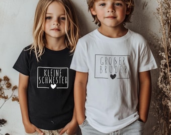 May include: A black t-shirt with the text KLEINE SCHWESTER and a white heart inside a rectangular frame, and a white t-shirt with the text GROßER BRUDER and a black heart inside a rectangular frame, both worn with light-colored pants.