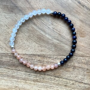 May include: A bracelet made with white, pink, and blue beads. The beads are separated by silver spacers.