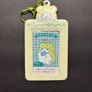 May include: A light yellow Marumofubiyori keychain photo holder with a cartoon character design. The holder has a rectangular shape with a clear window for a photo and a green clasp. The text "Marumofubiyori" is visible.
