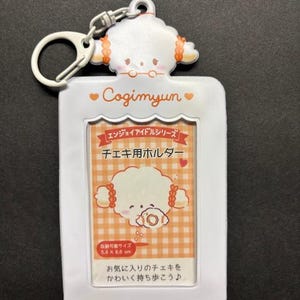 May include: White Cogimyun photo holder with a cartoon character design. The holder has a rectangular frame with a keychain attachment. The image area is 5.4 x 8.6 cm. Text includes "Cogimyun" and Japanese text.
