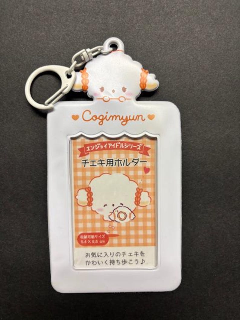 May include: White Cogimyun photo holder with a cartoon character design. The holder has a rectangular frame with a keychain attachment. The image area is 5.4 x 8.6 cm. Text includes "Cogimyun" and Japanese text.
