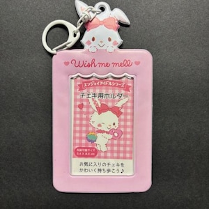 May include: A pink photo holder with a cartoon bunny design, a metal keyring, and the text "Wish me mell." The holder features a clear window for a photo and Japanese text. The holder measures 5.4 x 8.6 cm.