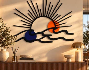 May include: A wall art piece featuring a black sunburst design with radiating lines above stylised black ocean waves. The composition includes a solid orange circle representing the sun and a solid dark blue circle representing the moon.