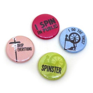 May include: Four colorful round buttons with text and graphics. One is pink with "DROP EVERYTHING", another is red with "I SPIN IN PUBLIC", a third is light blue with a spinning wheel and "I DO THE TWIST", and the last is green with "SPINSTER".
