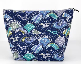 May include: A zippered pouch featuring a dark blue background with a repeating pattern of celestial elements including telescopes, planets, stars, suns with faces, and spacecraft in shades of light blue, teal, white, and purple.