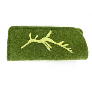 Op de afbeelding: Een rechthoekig etui van olijfgroen vilt met een geborduurde lichtgele zeedraak-silhouet op de voorzijde. Het etui heeft zichtbare donkergroene stiksels langs de bovenrand en een gevouwen constructie met een zachte, getextureerde afwerking.