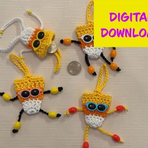 May include: Four handmade crochet candy corn ornaments with sunglasses and dangling limbs. The ornaments are yellow, white, and orange, with black and yellow or orange accents. The text "DIGITAL DOWNLOAD" is in a yellow box.