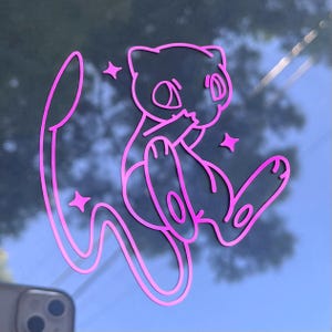 May include: A pink vinyl sticker featuring a cartoon-style illustration of a Mew character, with star accents. The sticker is a die-cut design, perfect for decorating laptops, water bottles, or other surfaces.