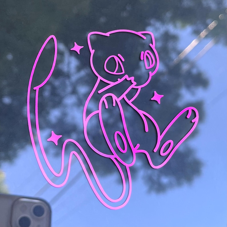 May include: A pink vinyl sticker featuring a cartoon-style illustration of a Mew character, with star accents. The sticker is a die-cut design, perfect for decorating laptops, water bottles, or other surfaces.