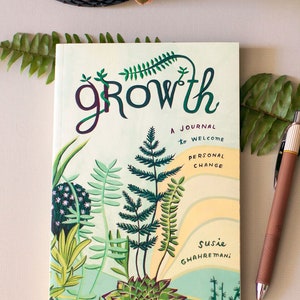 Może przedstawiać: Zielony dziennik z napisem "growth" w stylizowanym foncie. Okładka przedstawia kolorową ilustrację roślin i tekst "A journal to welcome personal change". Dziennik jest otwarty na stronie z cytatem Pema Chödrön: "I'm creating my future with every word, every action, every thought."