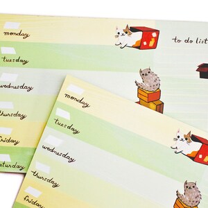 May include: A weekly planner pad with a green and yellow striped design. The pad features illustrations of cats in boxes and the text "to do list".