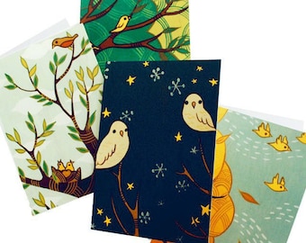May include: A collection of four greeting cards with bird illustrations. The cards feature various scenes, including birds on branches, in nests, and flying against a blue and green background. The illustrations are in a whimsical, cartoon style, with a focus on nature and wildlife.