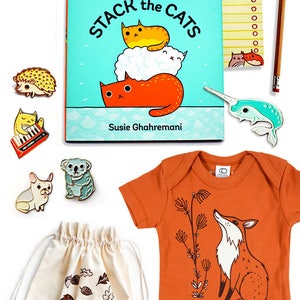 May include: A set of baby items including a book titled "Stack the Cats" by Susie Ghahremani, a light orange bodysuit with a fox graphic, a white drawstring bag with a squirrel graphic and the text "Snack Time!" and a variety of enamel pins.