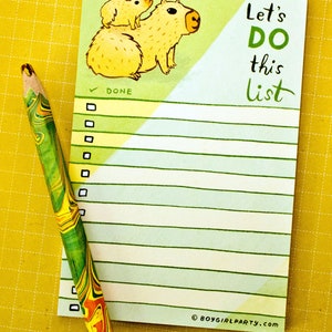 May include: A to-do list notepad with a green and blue striped background. The notepad features a cartoon illustration of two capybaras and the text "Let's DO this list".