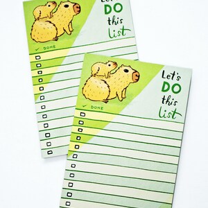 May include: A green and yellow notepad with a capybara illustration and the text "Let's Do This List". The notepad has a check box and lines for writing a to-do list.