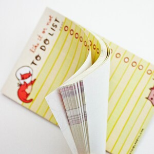 May include: A yellow and white striped to-do list notepad with the text "Like it or not, to do list" printed on the front cover. The notepad is folded in half and the pages are visible.