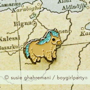 Op de afbeelding: Een kleine, lichtbruine emaille pin van een cartoon pony met een blauwe manen en staart. De pin is op een vintage kaart met de tekst "Karabogha" en "Aidindijk" zichtbaar.