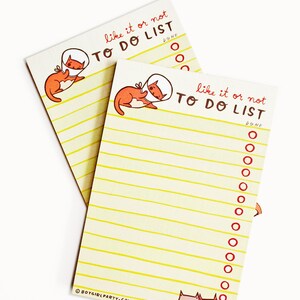 May include: Two yellow notepad sets with a cat wearing a cone of shame illustration. The notepad has the text "like it or not TO DO LIST" and a check box for "DONE".