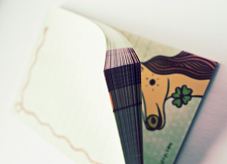 Op de afbeelding: Een gesloten boek met een kleurrijke illustratie van een cartoondier op de omslag. Het boek is gebonden met een dikke rug en heeft een witte achtergrond.