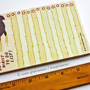 May include: A yellow notepad with a black cat illustration and the text "DO NOT WANT TO DO LIST!" printed on it. The notepad has a red border and a line of red circles at the top.