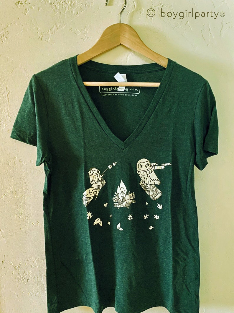 May include: A dark green v-neck t-shirt with a white graphic of three owls around a campfire. The text "boygirlparty.com" is printed on the shirt.