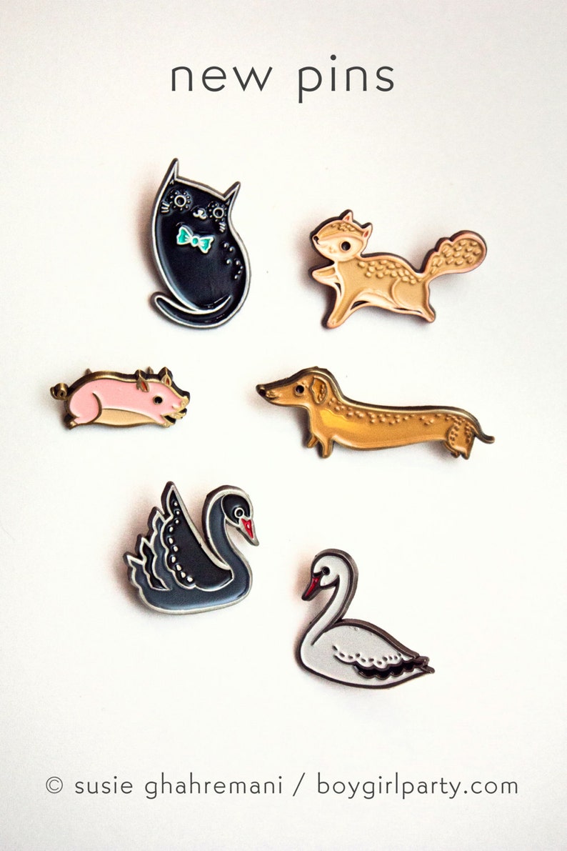 May include: Six enamel pins featuring various animals: a black cat with a bow tie, a brown squirrel, a pink pig, a brown dachshund, a black swan, and a white swan. The pins are arranged on a white background with the text "new pins" at the top.