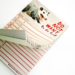 May include: A white notepad with red lines and a black and white illustration of a possum. The notepad has the text "DO NOT WANT to do list" printed on the front.